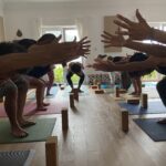 Braços estendidos em utkaṭāsana, a postura da cadeira, com blocos sob as mãos