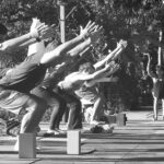 Em preto e branco: a turma inteira em utkaṭāsana, ao ar livre