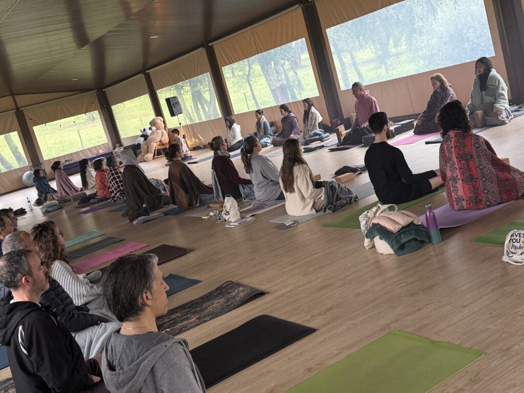 Turma sentada numa sala ampla, ouvindo a aula.