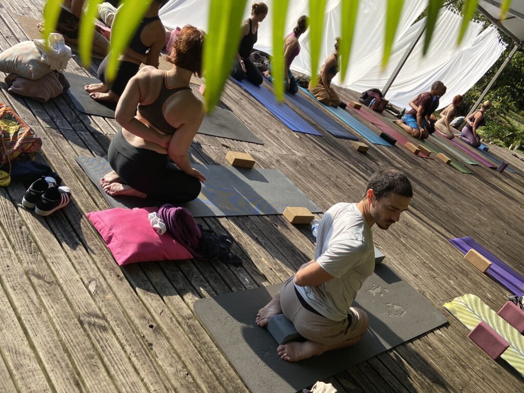 Prática num deck de madeira, sob bandeirolas verdes.