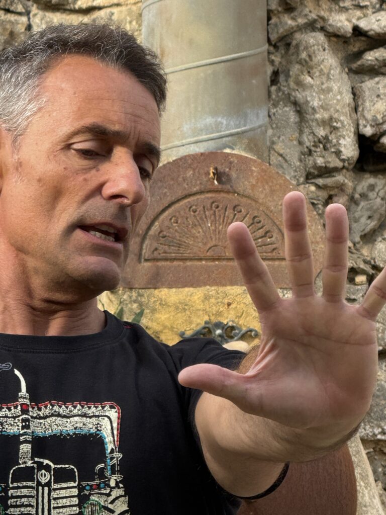 Pedro de perto, com a mão aberta num gesto de explicação